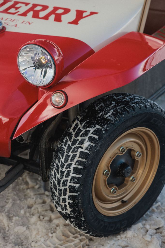 A detail shot of a race car tire on a snowy surface.