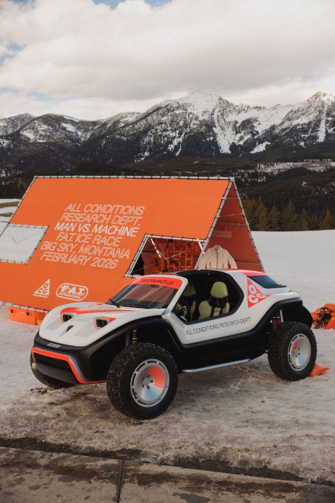 A white, black and orange race car with an orange NIke ACG-branded tent behind it at the FAT Ice Race in Big Sky, Montana.