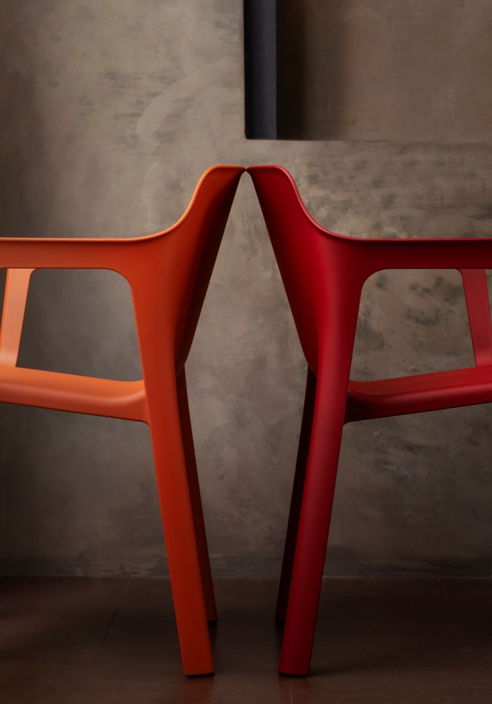 Two red Linnea chairs facing back to back, shot from a side view.