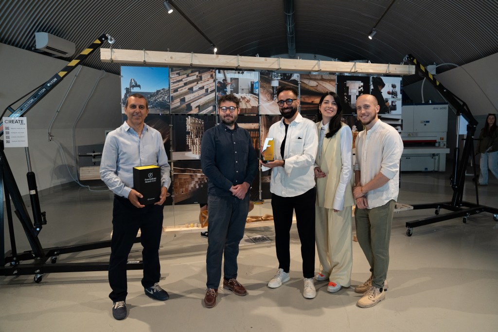 The team from SDU Create standing in front of their exhibition, with one woman holding the Fuorisalone Award.