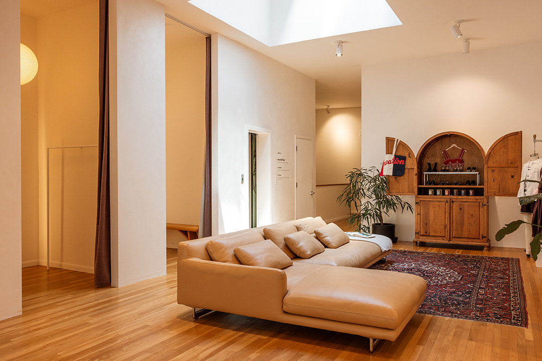 An upstairs level at Frances May with a large leather sofa and a vintage arched wood cabinet.