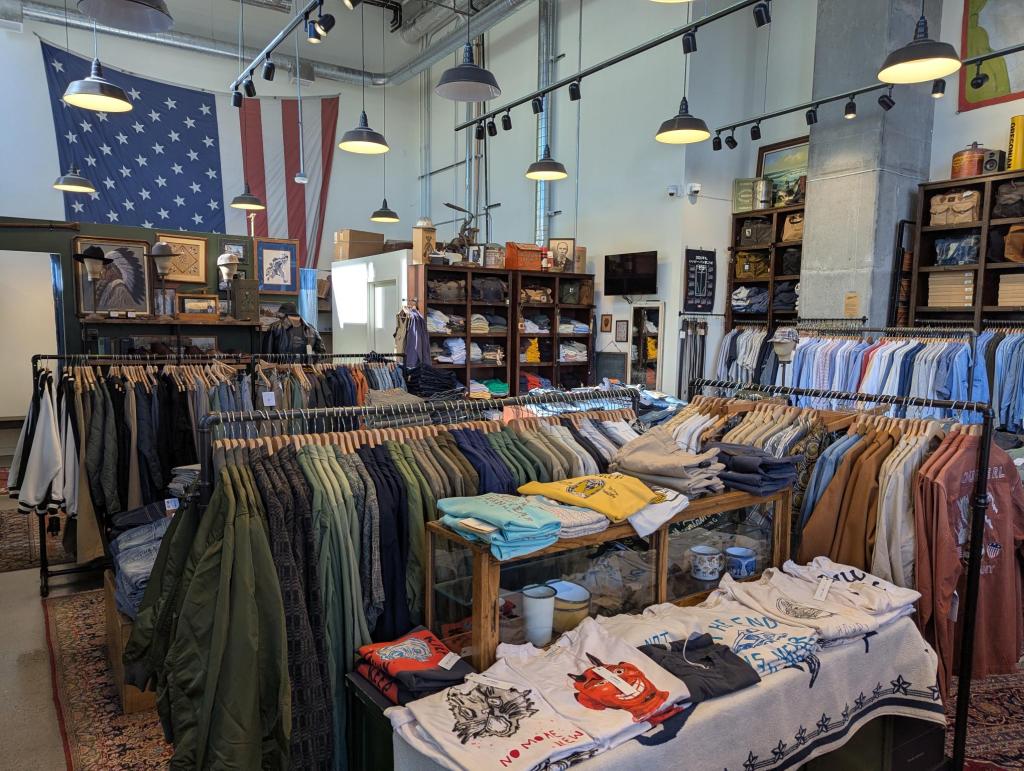 An interior shot of MILWORKS with an antique American flag hanging on the wall, vintage shelving and racks of clothing.