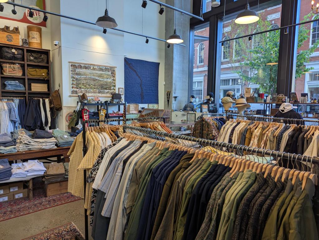 An interior view of MILWORKS, looking towards the cash register and the street window, with a large indigo textile hanging on the wall.