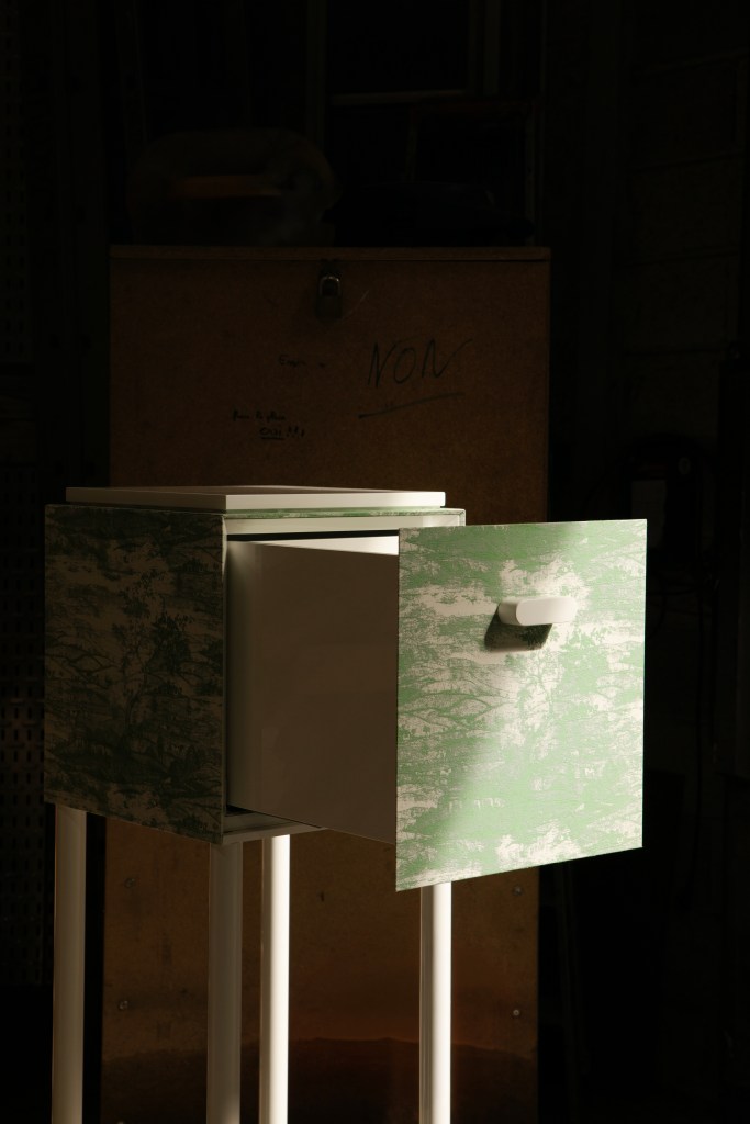 A detail of a green and white side table by Francesco Balzano with its drawer open.