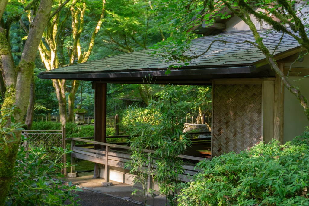 The Tea House at Portland Japanese Garden with lush green trees in the background.