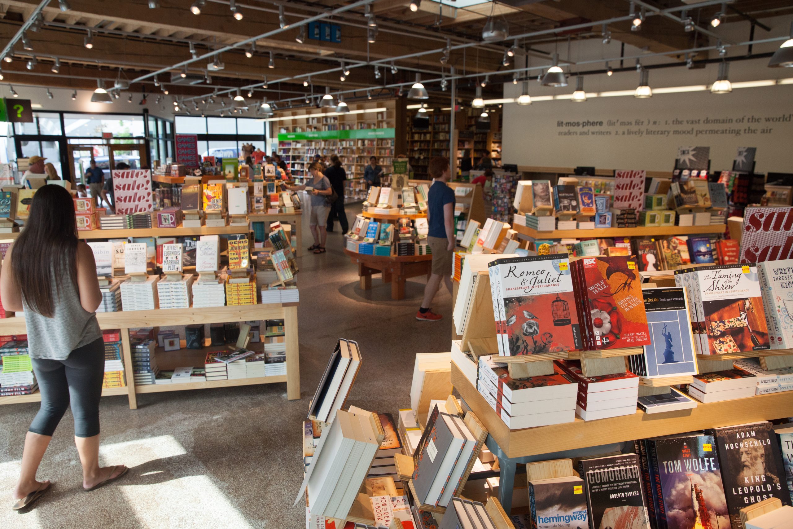 An interior shot of Powell's Books with many light wood shelves, books and high industrial-style ceilings.