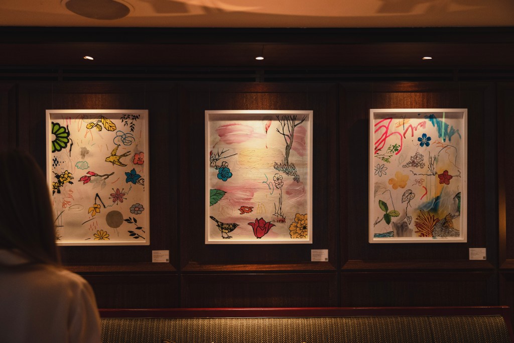 Three framed works of art by Dan Baldwin hanging on the dark wood wall at the bar at 45 Park Lane.