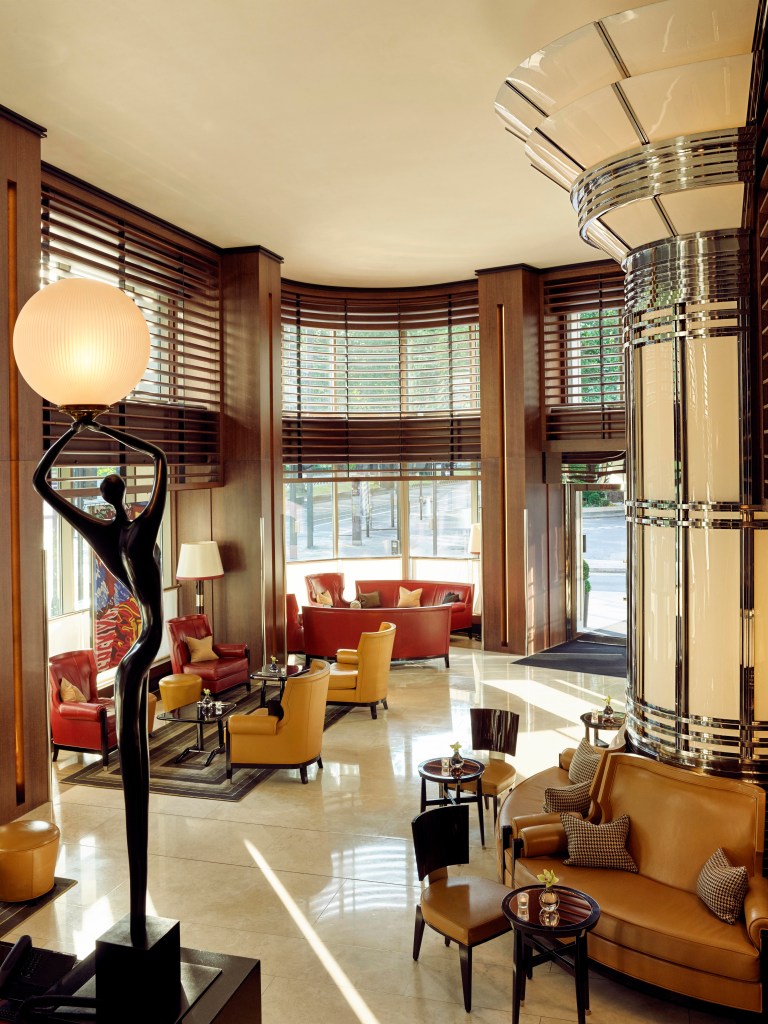 The bright lobby at 45 Park Lane with Art Deco architectural details and a large, elongated statue of a figure holding a light.