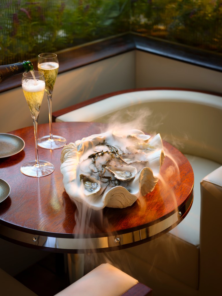 A dish of seafood and two glasses of sparking wine sitting on a table at the 45 Park Lane outdoor summer dining terrace.