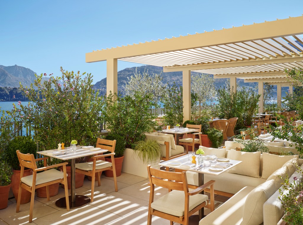 An outdoor terrace at Lake Como EDITION with a pergola and mountain views.