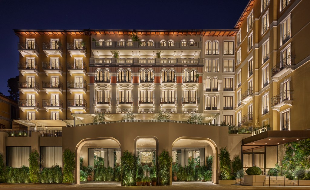 The exterior of Lake Como EDITION Hotel, shot at night with a grand, illuminated entrance.