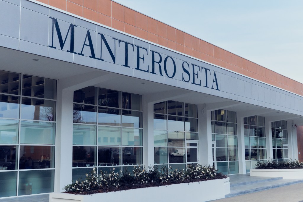 The exterior of Mantero Seta with a brown roof and blue sky in the background.