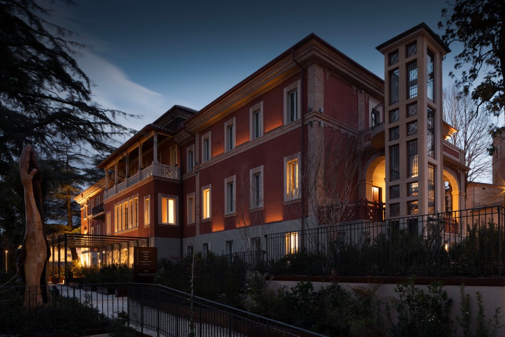 The exterior of Interno Marche Hotel, shot at nighttime, with lights on in the windows.