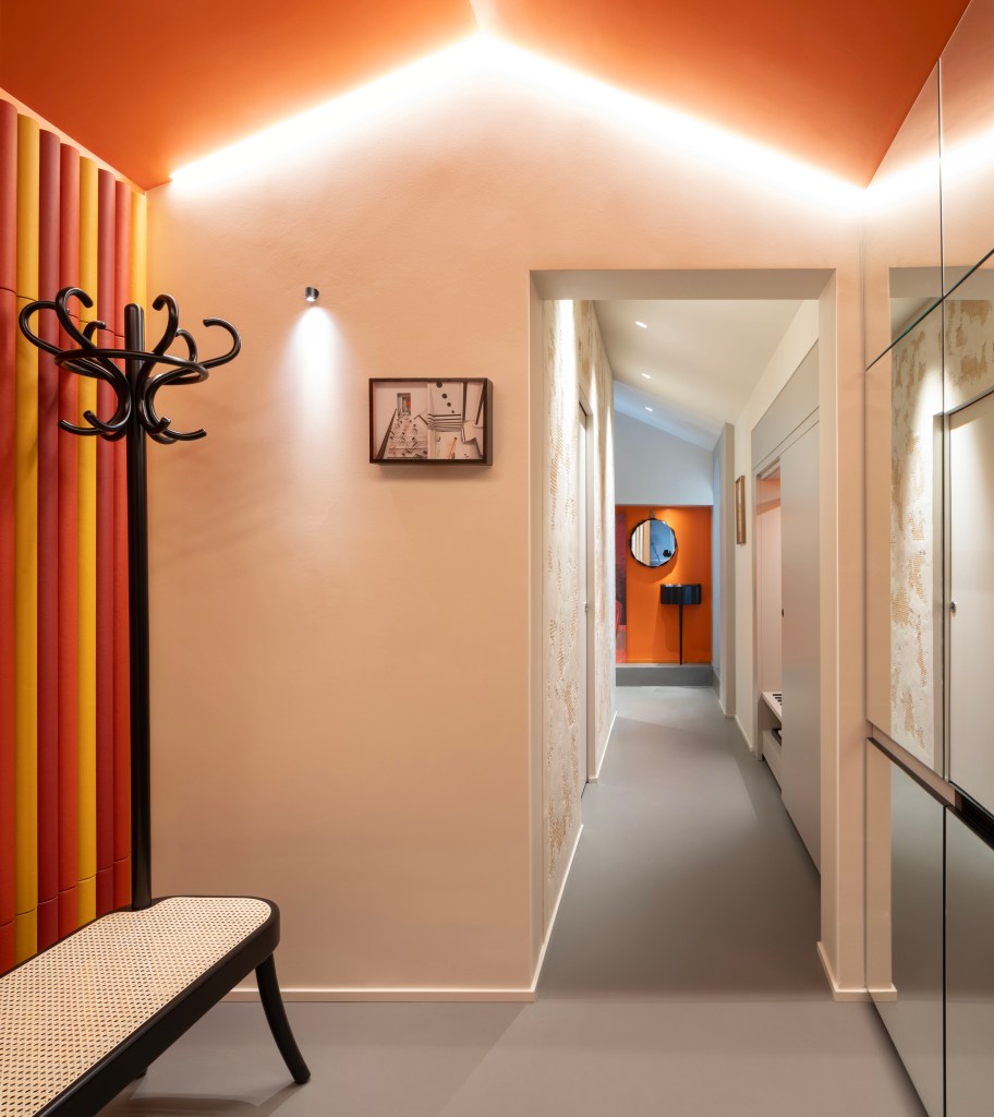 A warm peach room with a deep orange ceiling and a hallway that leads to another area of a guest room at Interno Marche.