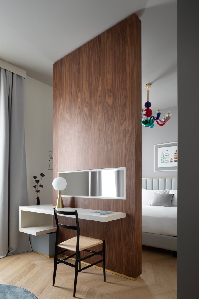 A guest room at Interno Marche with a wood panel and desk bisecting the sleeping area.