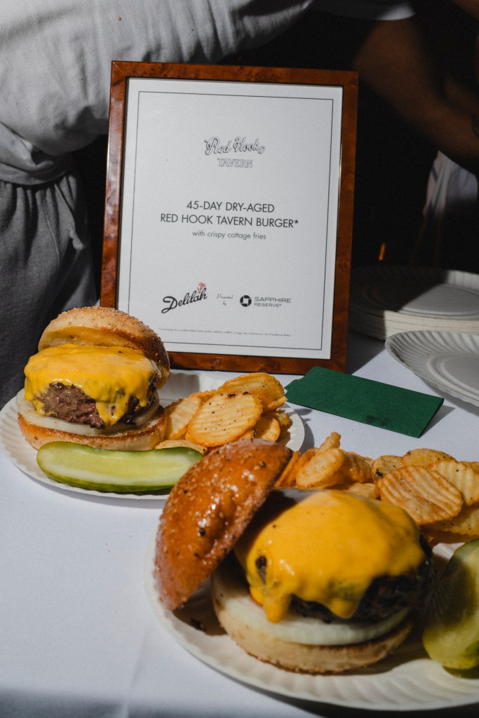 Two plates of cheeseburgers with a small white menu sign propped up behind the back plate.