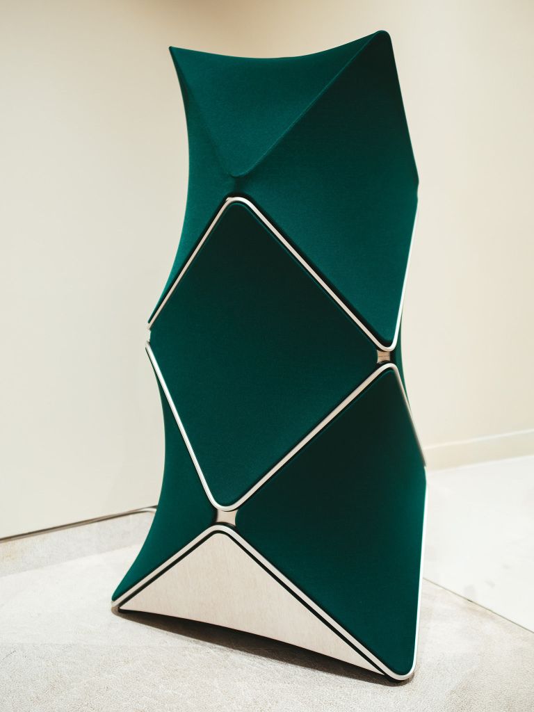 A green, geometric-shaped Bang & Olufsen speaker on a cream background.