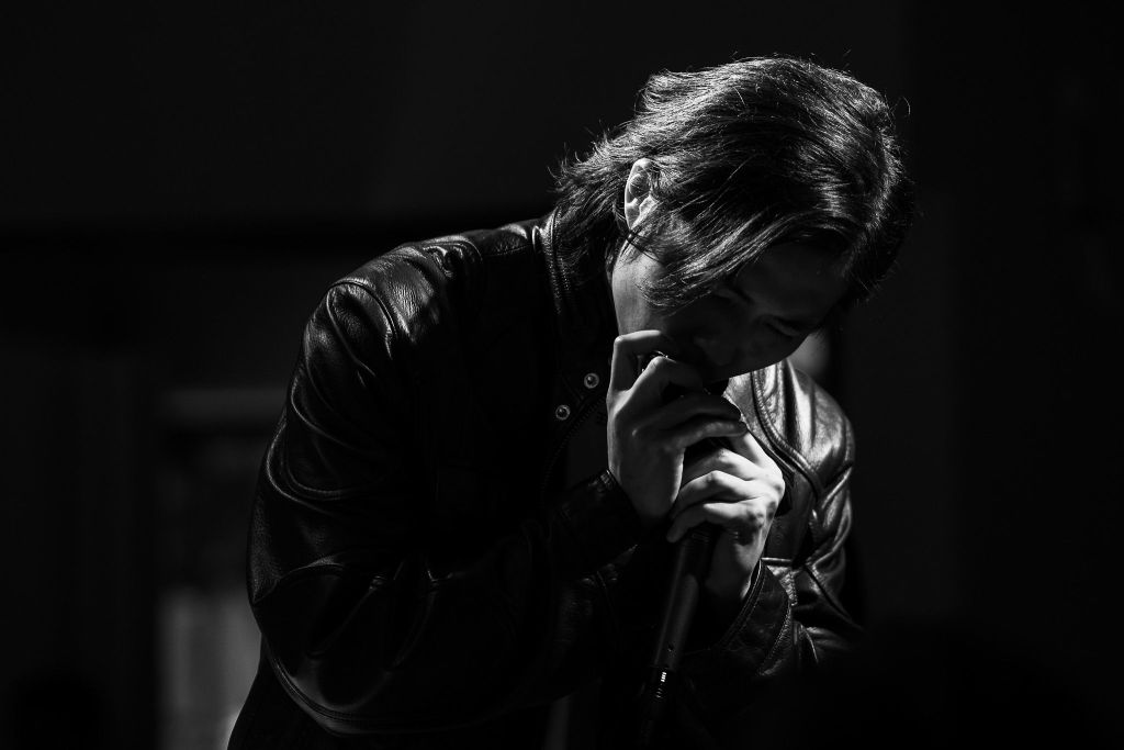 A black and white photo of a person singing into a micorphone.