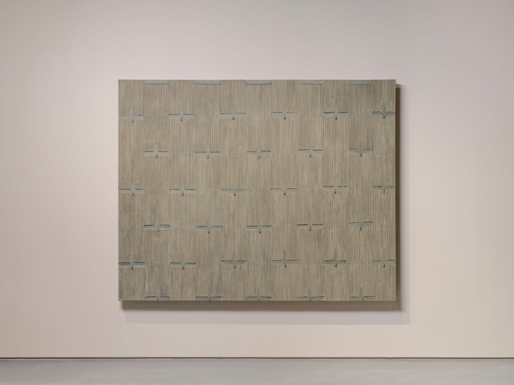 An image of a tan abstract painting on a white wall in linear marks on Korean hanji paper.