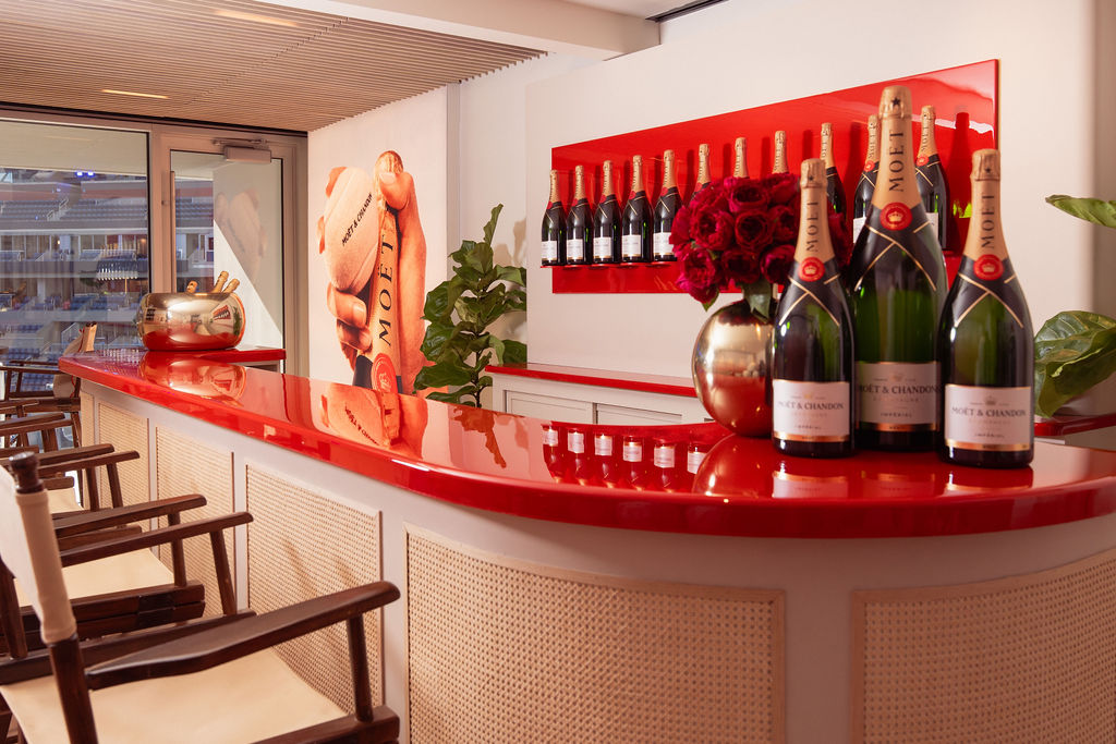 The Moët & Chandon suite's red bar wtih a line of Champagne bottles lining the wall behind it.