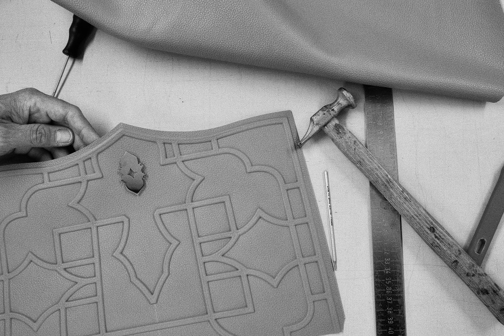 An overhead black and white shot of an artisan making a leather Dellaluna bag.