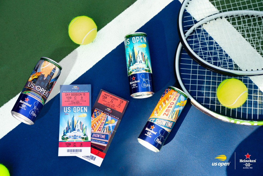 An overhead shot of a few Heineken cans, vintage US Open ticket stubs, tennis rackets and balls, displayed on a tennis court.