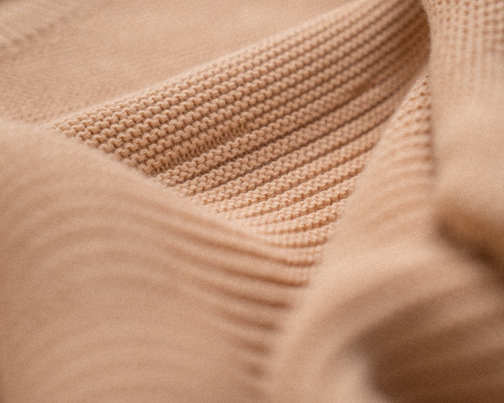 A detail of a tan knit sweater.