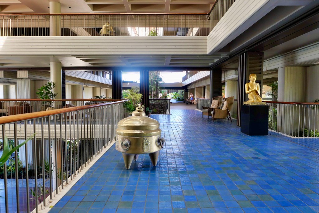 Two large pieces of brass art displayed alongside the blue tile floor of the Mauna Kea Resort atrium.