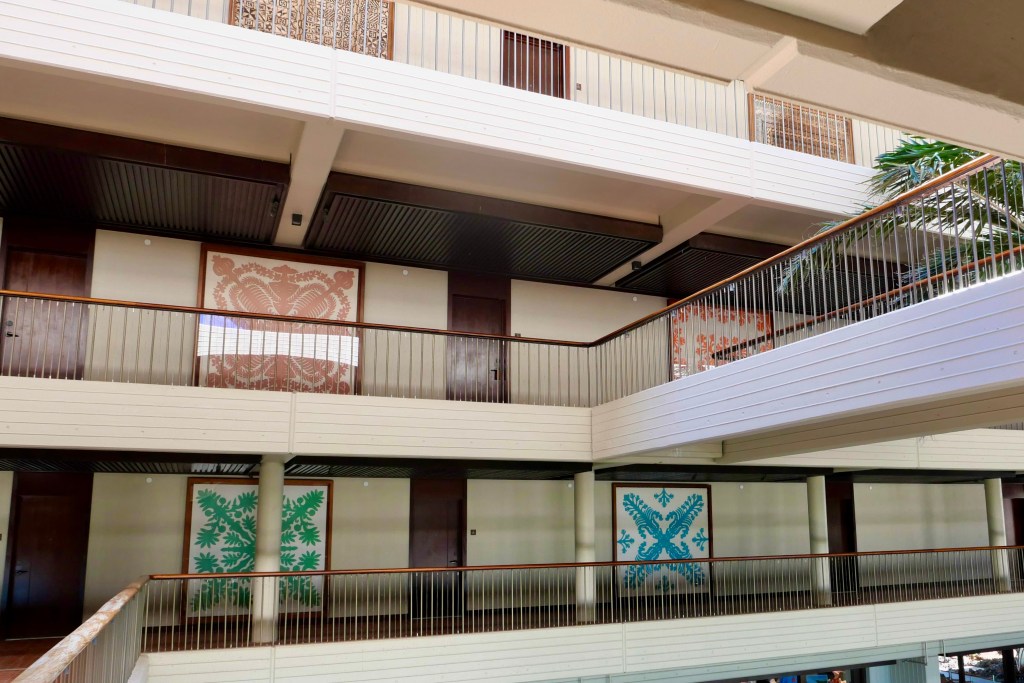 Large handmade quilts displayed in custom frames along the hallways at Mauna Kea Resort.
