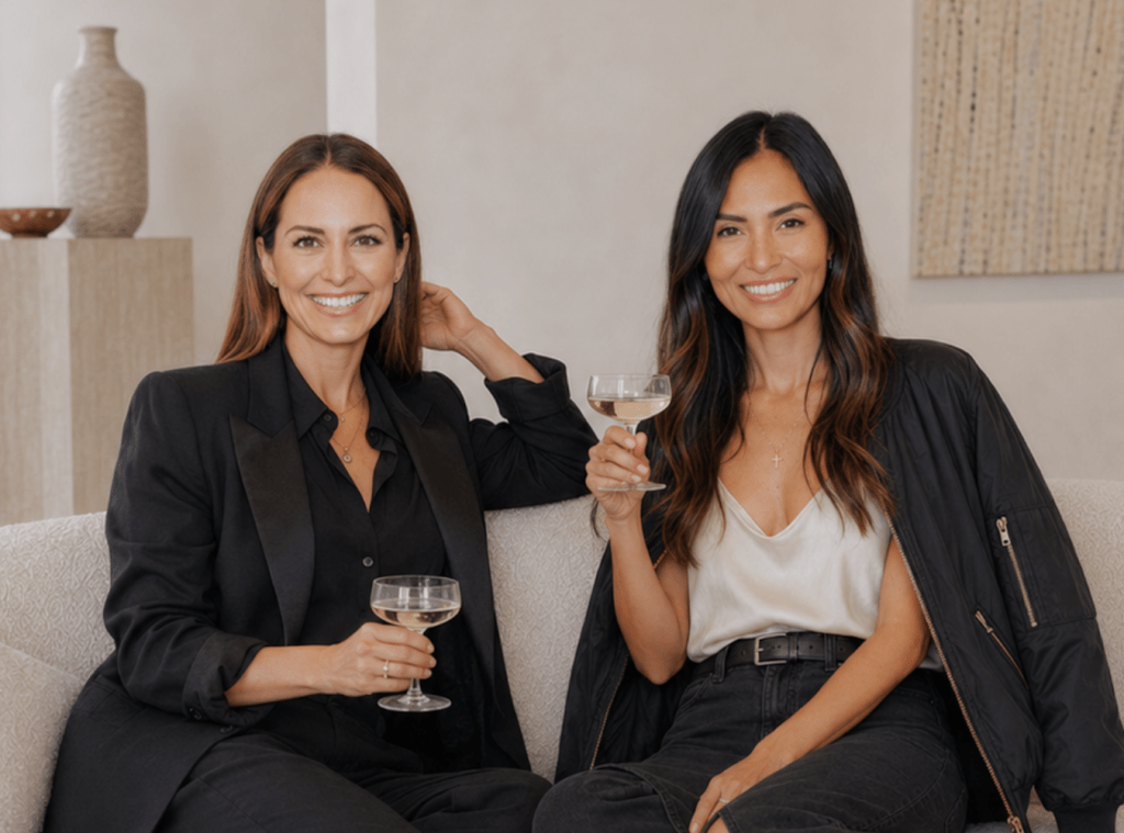 Allison Parc and Sam Lim Achatz sit on a light colored sofa, each holding a drink.
