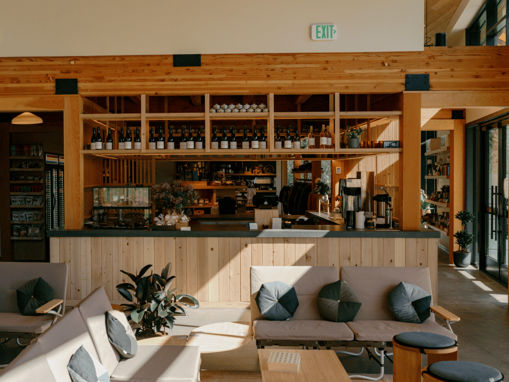 A large room with a wood paneled bar area, small couches set around a low table, and sunlight streaming in from the upper right.