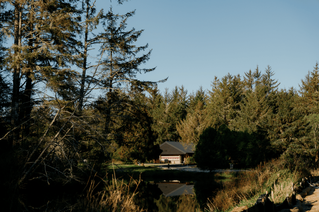A pulled-back shot of woods with a low building in the middle.