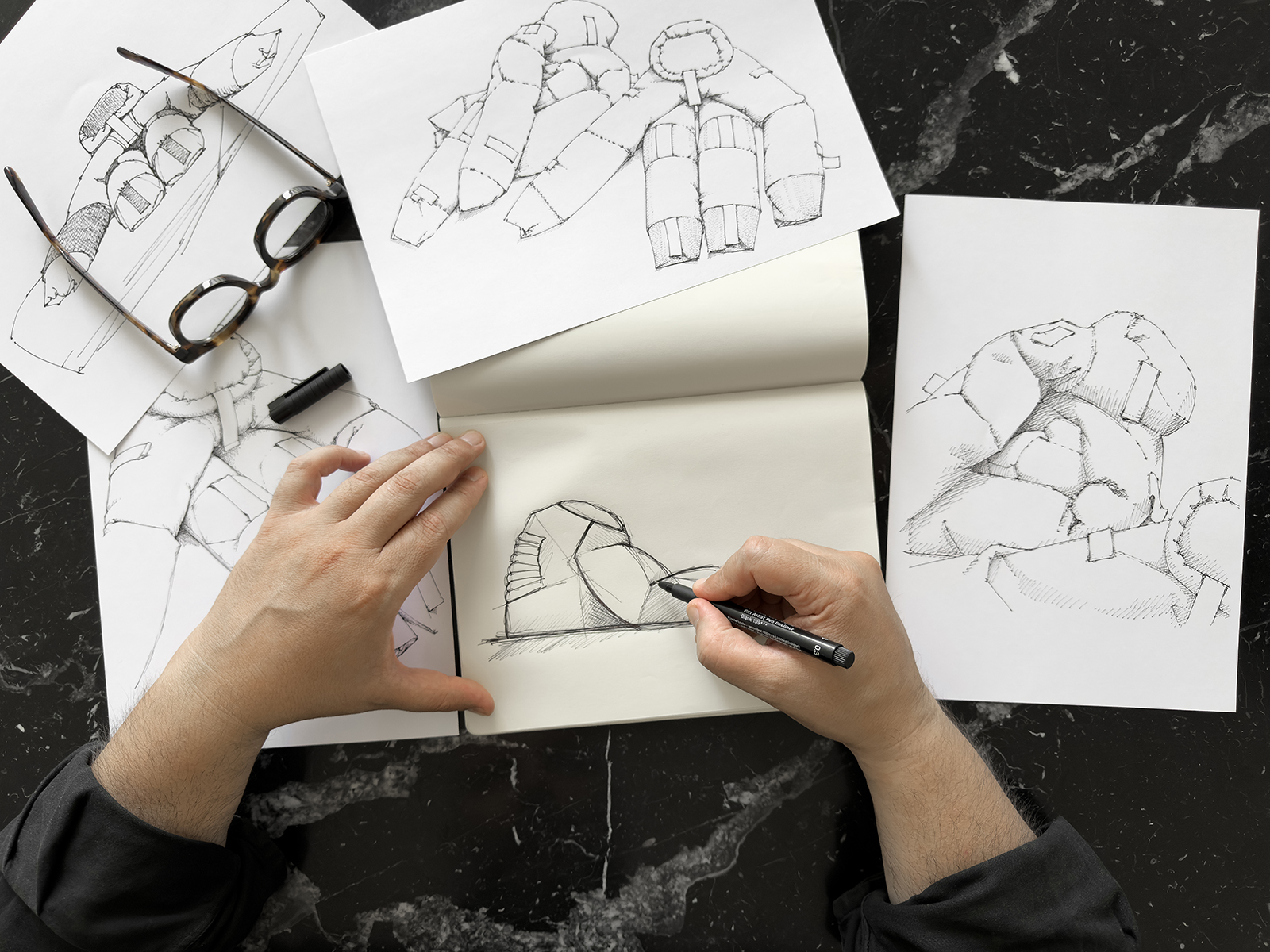 A pair of hands sketching designs of Soft Monuments.