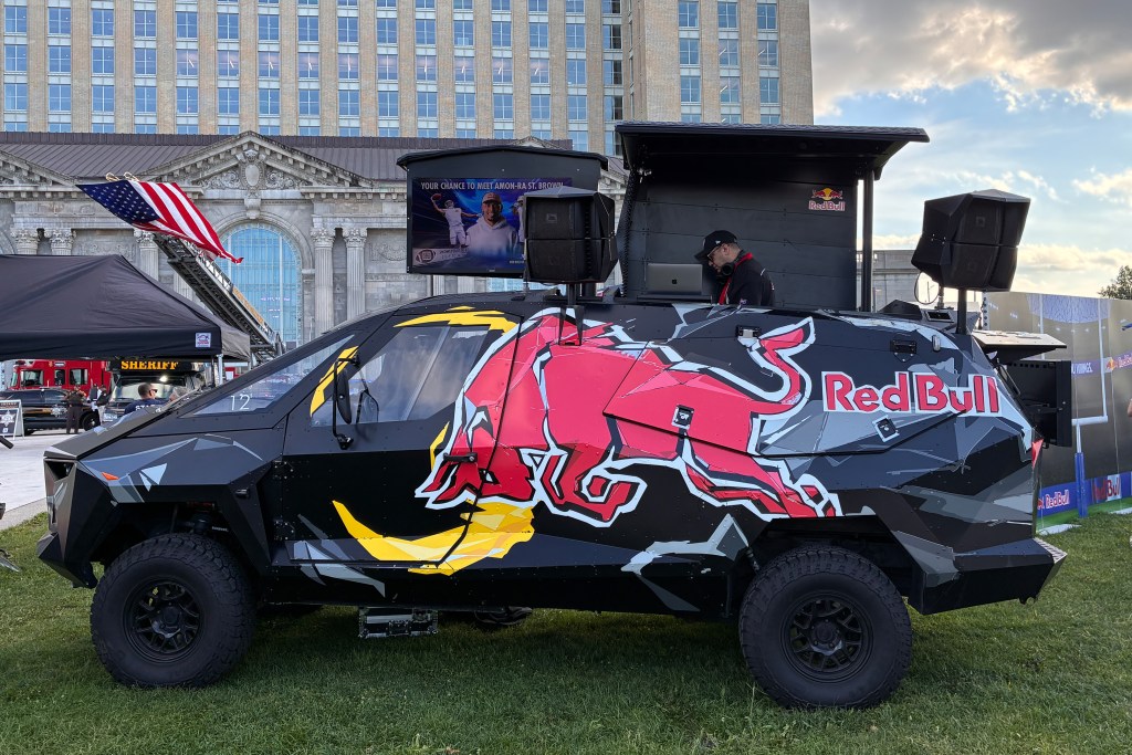 A tactical SUV with Red Bull branding with a DJ playing out of its open top.