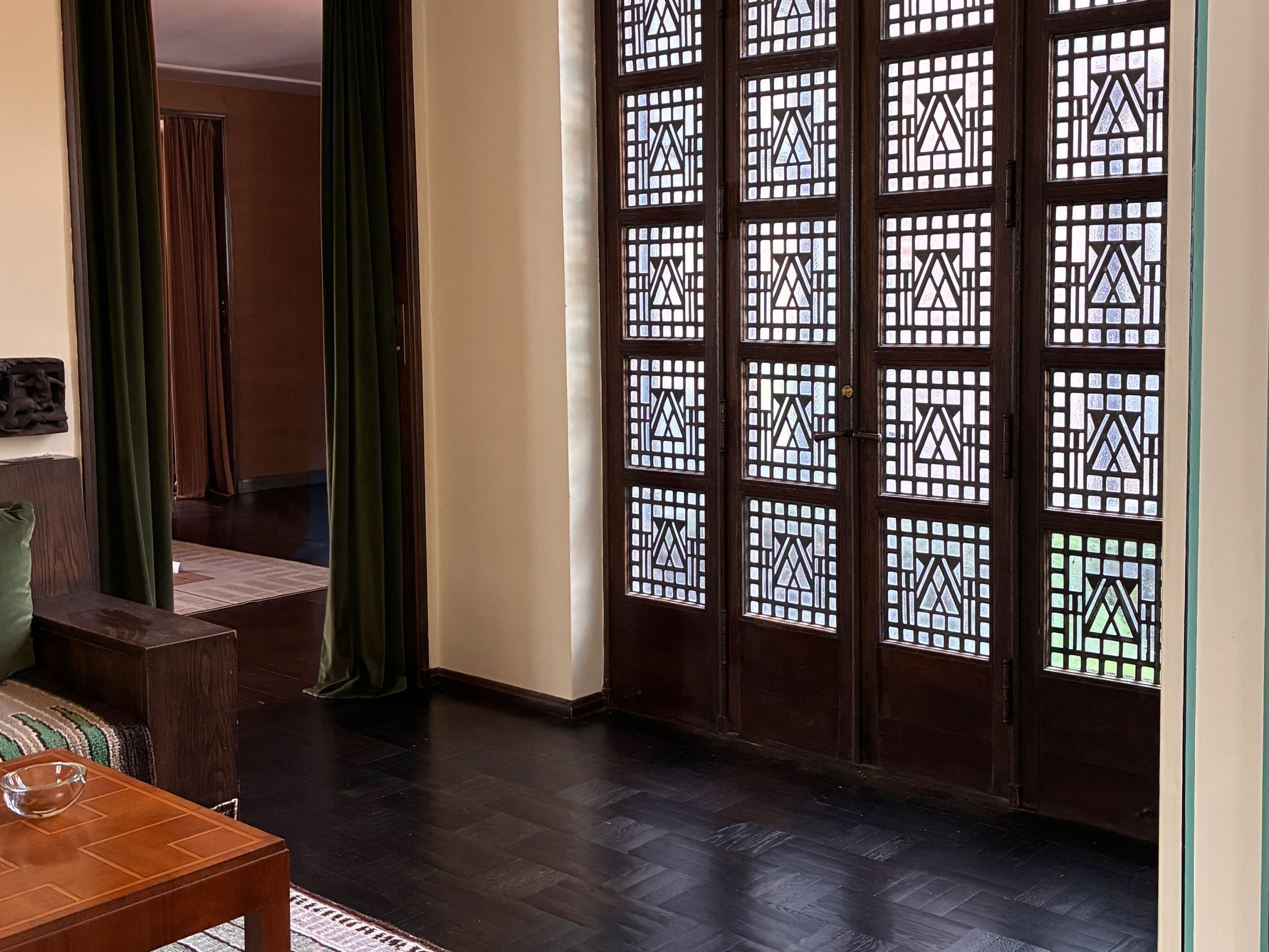 A corner of a room with a tall multi-paned window in an Art Deco style.