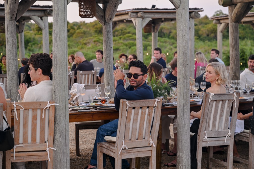 A large outdoor dining table full of people as they look onward to the left of frame.