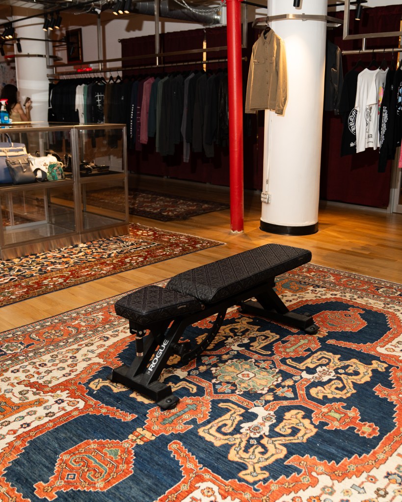 A black leather workout bench with an embossed design on top of an ornate Persian rug.