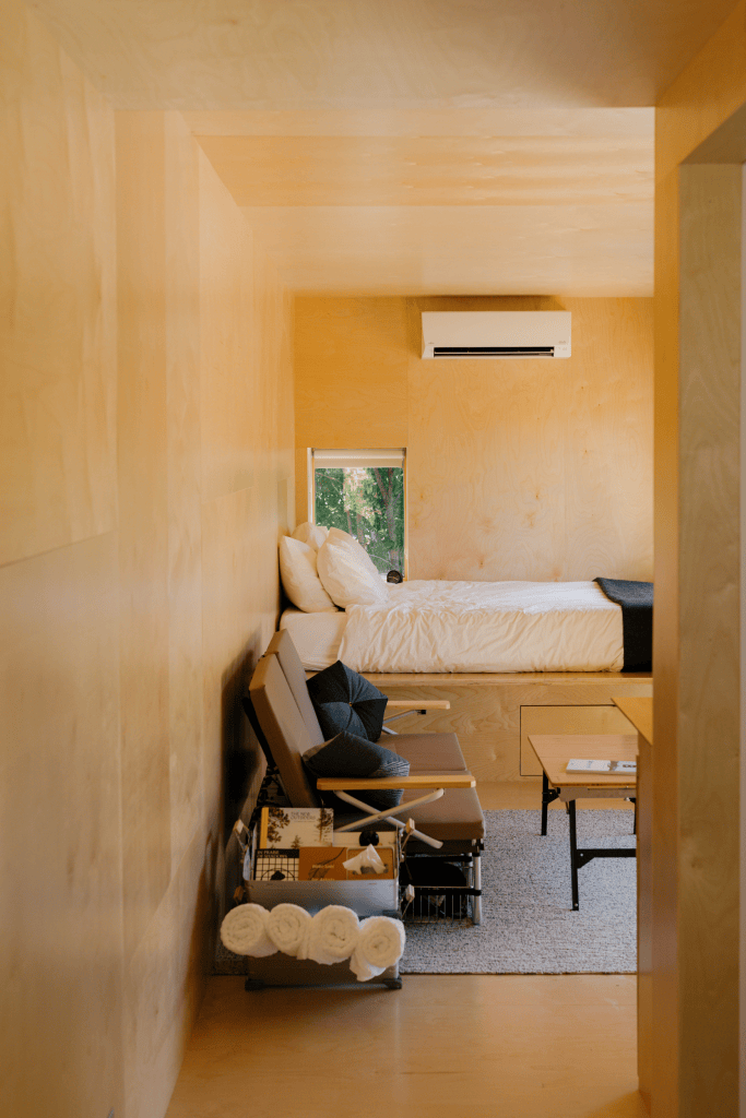A wood-walled interior room with a bed tucked in at the end.