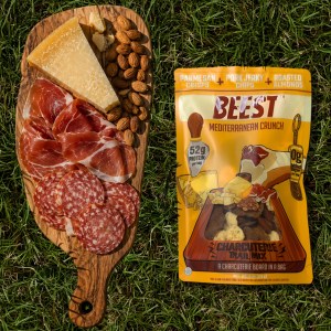 A wood board with salami, ham, parmesan cheese and roasted almonds