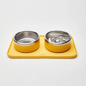 Trot's water bowl, puzzle food bowl, and mat, shown in yellow