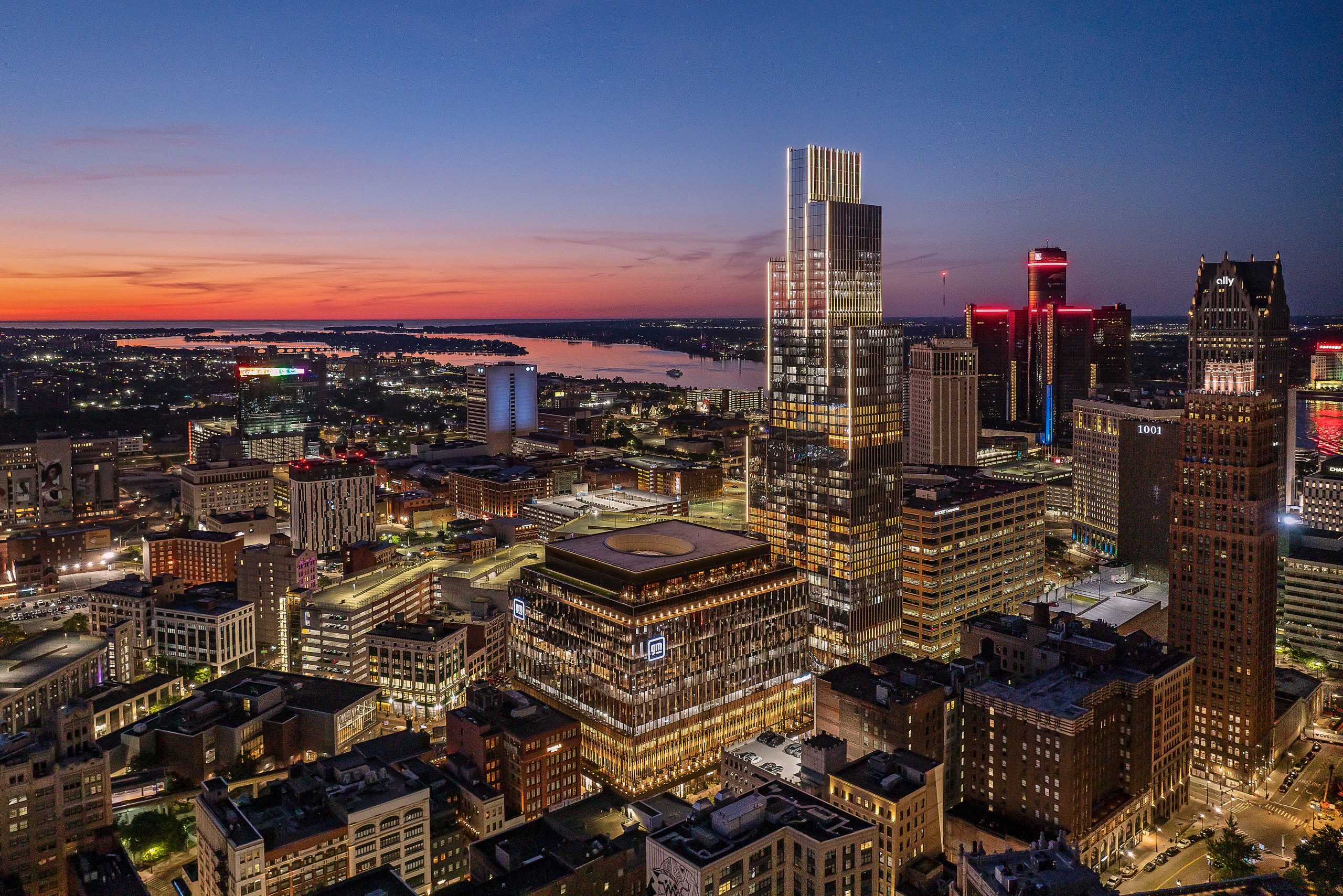 An exterior aerial view of downtown Detroit with illuminated buildings and a sunset.