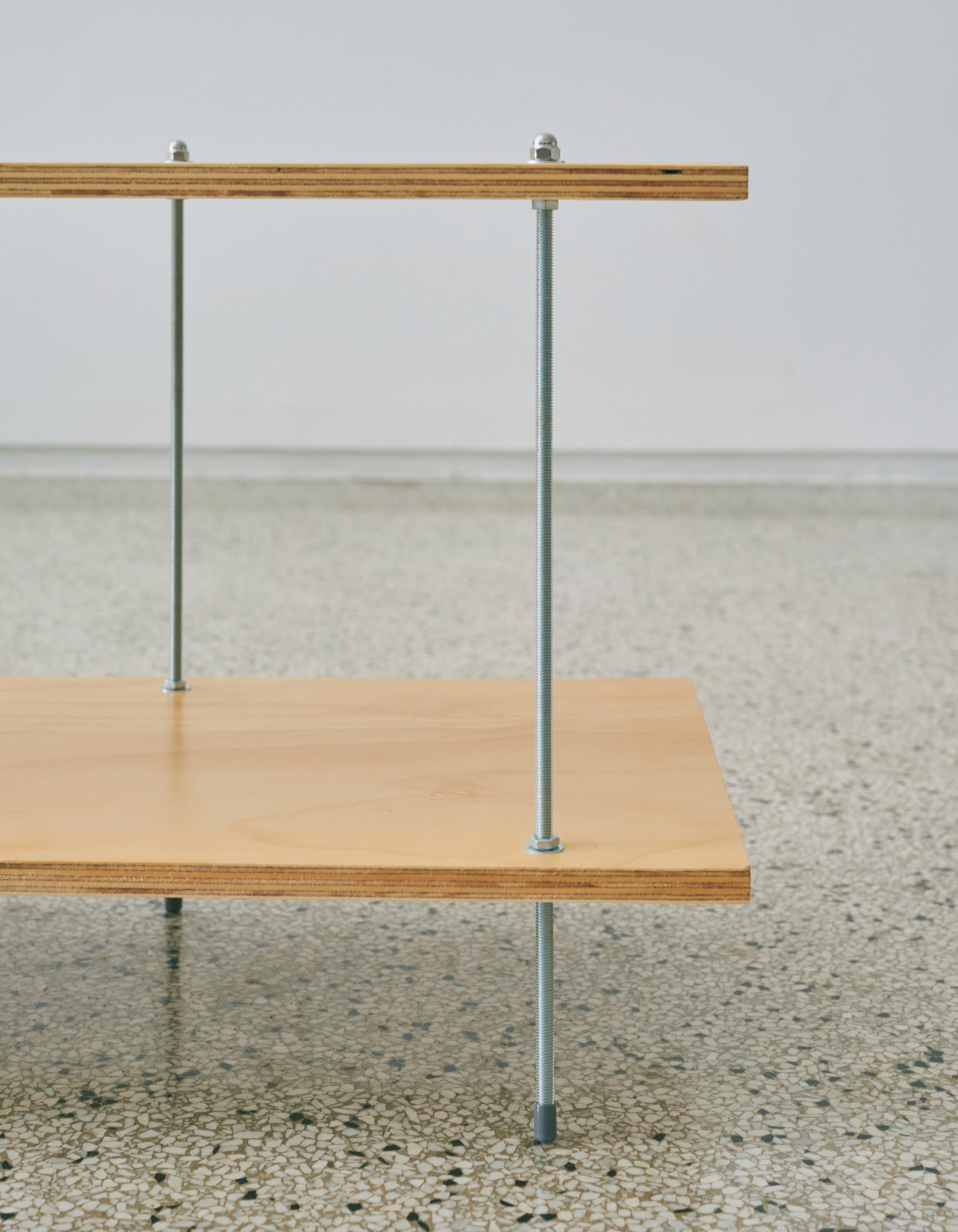 A detail of a light wood shelf with metal rods.