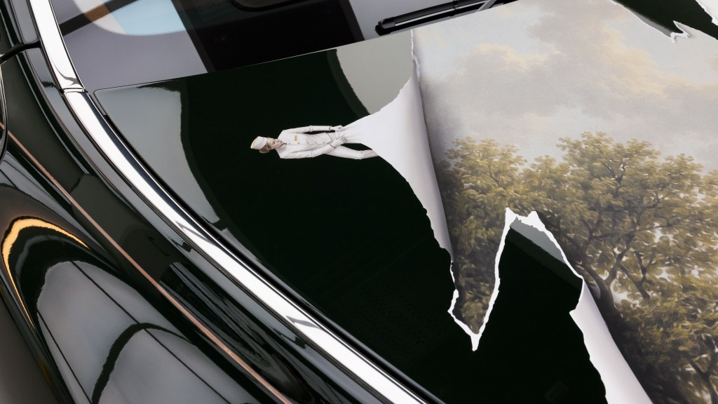 A detail of an art car by KOZO depicting a hotel employee pulling back paint to reveal an idyllic British landscape.