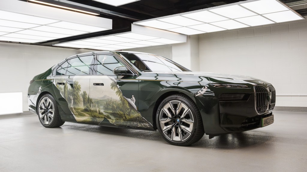 A black art car covered in artwork by KOZO, made to look like the paint is peeling to reveal an idyllic British landscape.