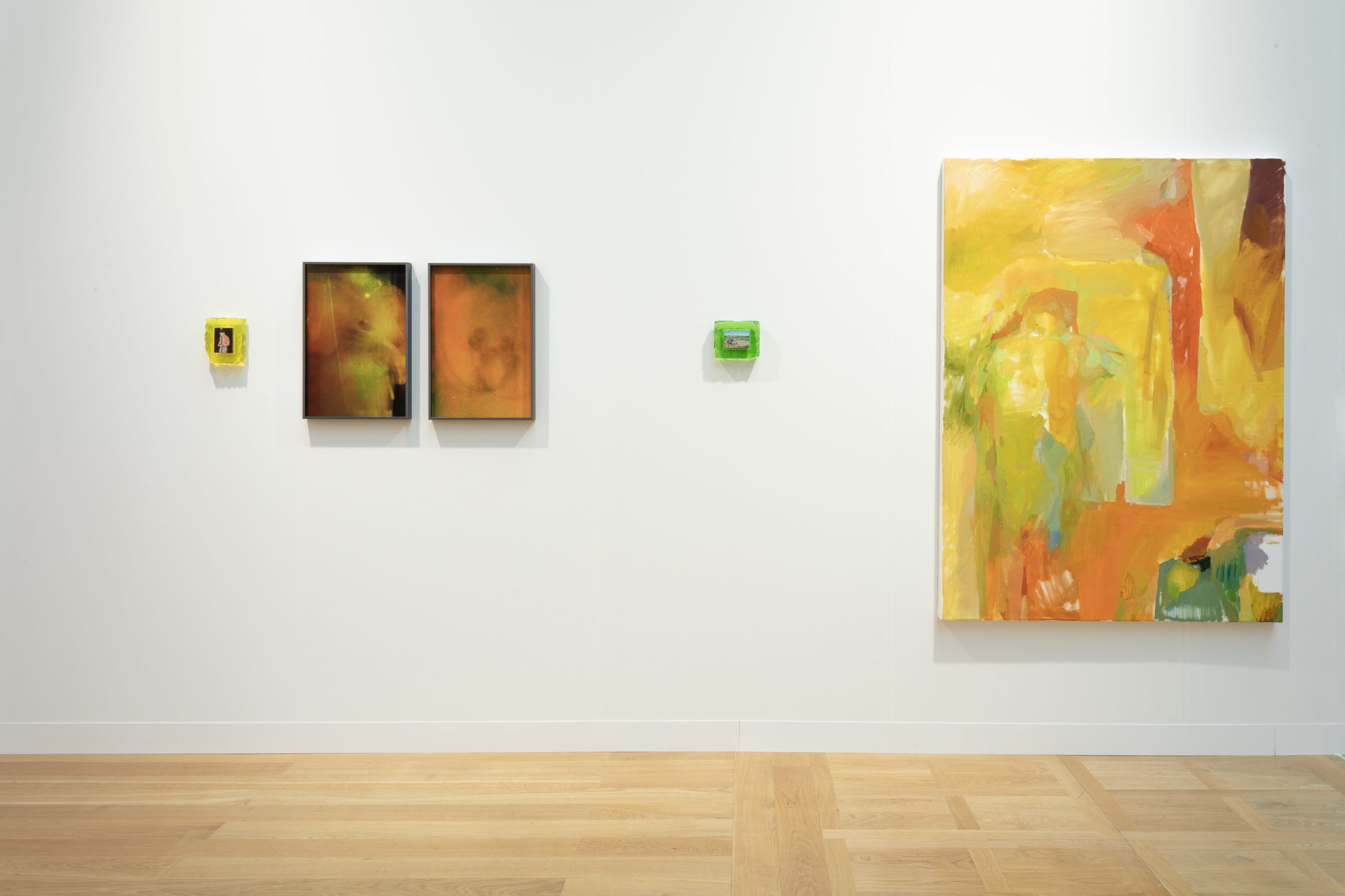 A row of five different-sized artworks hanging on a while gallery wall.