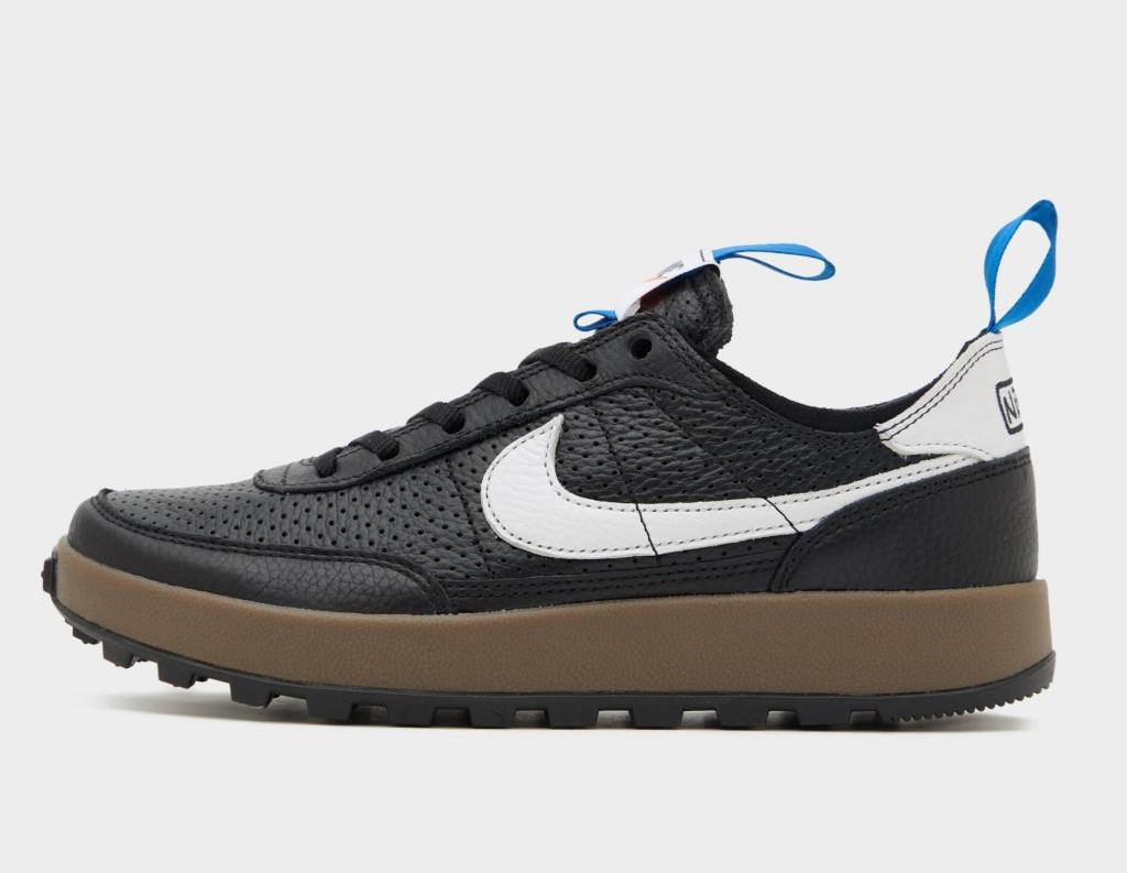 A profile view of a black Nike sneaker with a white swoosh and bright blue pull tabs on the heel.