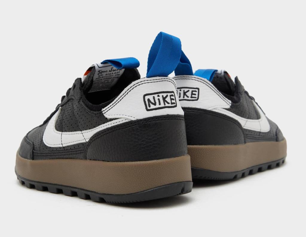 The back view of a pair of black and white Nike sneakers with bright blue pull tabs at the ankles.