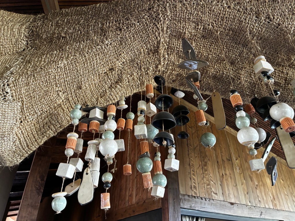 A detail of a sculptural piece hanging from the ceiling, made of sisal and different colored and shaped beads.