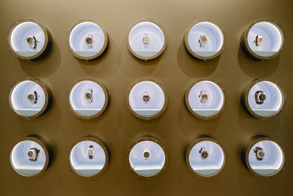A wall of round glass windows with a luxury watch inside each one.