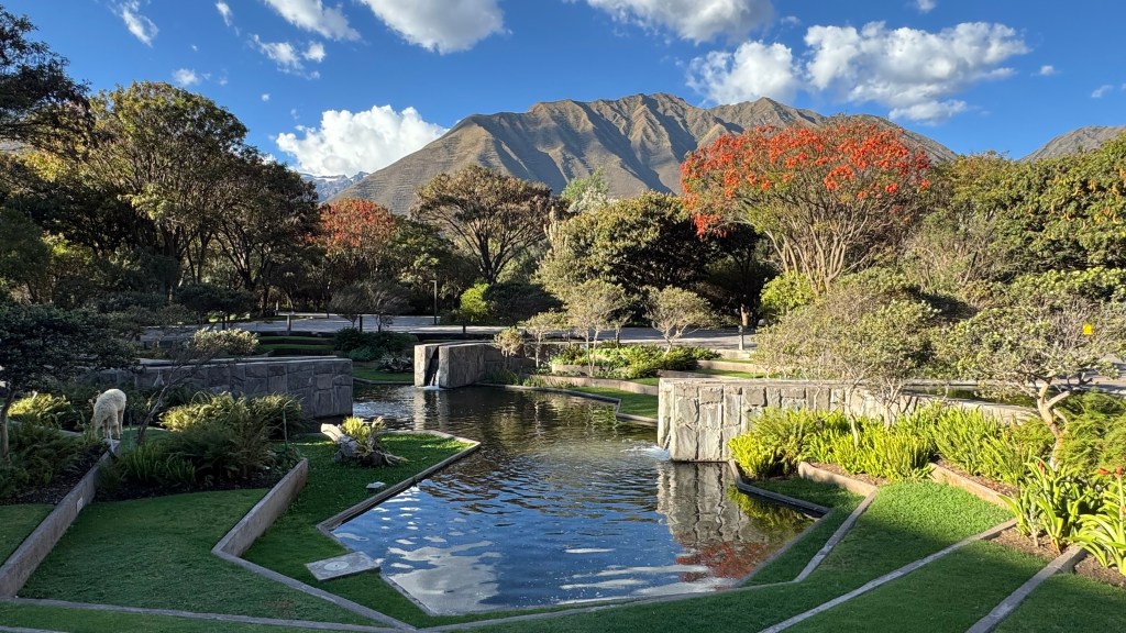 A view of the grounds at Tambo del Inka with geometric ponds built into the land and the Andes in the background.